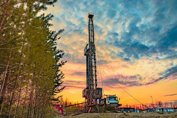 Drilling a deep well mobile drilling rig in an oil and gas field. The field is located in the Far North in the taiga. Beautiful dramatic sunset sky in the background.