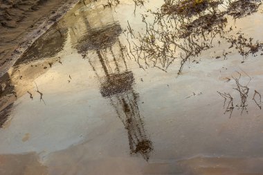 Bir yağ birikintisi içinde bir petrol kulesi bulanık görüntü yansıması. Ölü bitkiler. Petrol ve gaz sondajı yaparken çevre kirliliği kavramı. Petrol ve gaz üretiminde ekoloji sorunları.