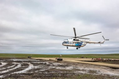 Bir kutup havacılık helikopteri kuzey tundra uzak bir helikopter pistine inmeye hazırlanıyor, çok uzak olmayan bir sondaj petrol kuyusu. Yalan ekipmanları ile ahşap platform. Kasvetli kuzey gökyüzü. Sondaj cıların ve petrol işçilerinin gelişi bekleniyor.