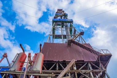 Kuleli sondaj kulesi. Alt katta sondaj ekipmanları var. Kuzey sahasında petrol ve gaz üretimi için derin bir kuyu açılan bölgede sondaj yapılıyor. Yaz günü. Mavi bulutlu gökyüzü.
