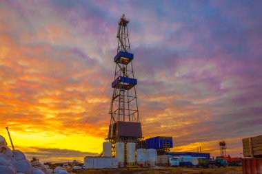 Drilling rig with a tower tower. Downstairs is the drilling equipment. A deep well is being drilled in the northern field for oil and gas production. Summer polar night. Beautiful sky with backlit clouds. clipart