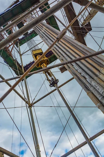 Location of equipment inside the oil and gas drilling rig. Drill pipes stand upright. Lifting system. View from bottom to top. Work is underway to raise drill pipes from the well.