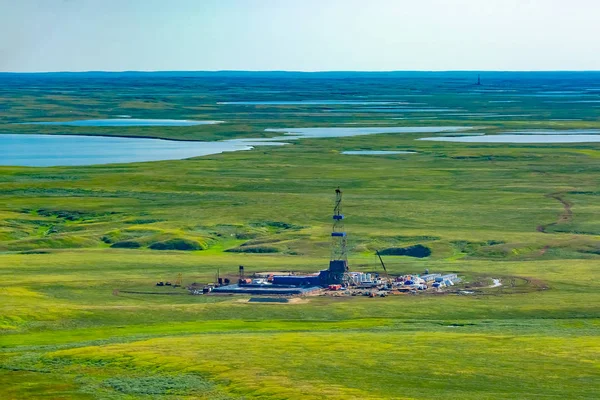 Kuzey tundrasındaki bir petrol sahasında sondaj kulesi ve teçhizatı. Bir helikopterden en iyi görüntü. Kuzey Kutup Dairesi'nin ötesindeki göllerle yeşil yaz tundrası.