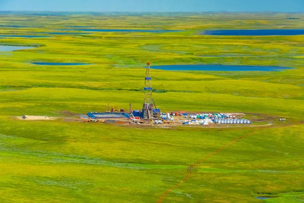 Kuzey tundrasındaki bir petrol sahasında sondaj kulesi ve teçhizatı. Bir helikopterden en iyi görüntü. Kuzey Kutup Dairesi'nin ötesindeki göllerle yeşil yaz tundrası.