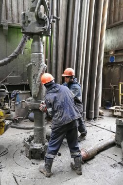 Novy Urengoy / Rusya - Mayıs 03 2020: İki sondaj işçisi, güç anahtarı kullanarak sondaj ve sondaj aletini kırmanın yanı sıra petrol ve doğalgaz üretimi kuyusuna akıtıyorlar.