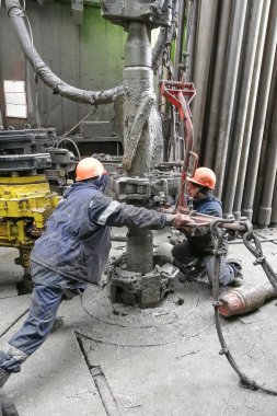 Novy Urengoy / Rusya - Mayıs 03 2020: İki sondaj işçisi, güç anahtarı kullanarak sondaj ve sondaj aletini kırmanın yanı sıra petrol ve doğalgaz üretimi kuyusuna akıtıyorlar.