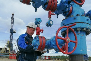 Novy Urengoy / Rusya - 29 Mayıs 2020: Bir petrol ve gaz üretim uzmanı, bir dizüstü bilgisayar kullanan bir jeolog, petrol ve gaz üretiminin teknolojik parametrelerini ve modellerini bir kuyudan belirler. Çeşmeye manometreler ve termometreler yerleştirildi