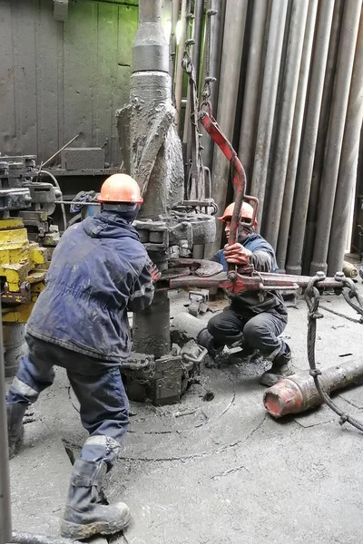 Novy Urengoy / Rusya - Mayıs 03 2020: İki sondaj işçisi, güç anahtarı kullanarak sondaj ve sondaj aletini kırmanın yanı sıra petrol ve doğalgaz üretimi kuyusuna akıtıyorlar.