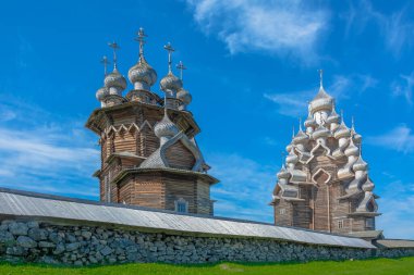 Tarihi, mimari ve etnografik açık hava müze rezervi Kizhi. Tahta bir kilisede uzaktan bir manzara, Onega Gölü 'ndeki bir adada çan kulesi. Önünde taş bir duvar var.   