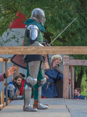 Tver / Rusya - 29 Eylül 2020: Ağır ortaçağ zırhlı bir şövalye kılıçlarla bir rakiple savaşmaya hazırlanıyor. Demir bir miğfer ve kalkan tarafından korunuyor. Ortaçağ Avrupa şövalye turnuvalarının tarihi yeniden yapılandırması