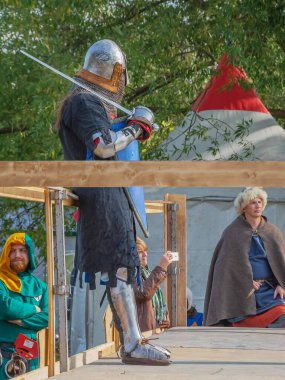 Tver / Rusya - 29 Eylül 2020: Ağır ortaçağ zırhlı bir şövalye kılıçlarla bir rakiple savaşmaya hazırlanıyor. Demir bir miğfer ve kalkan tarafından korunuyor. Ortaçağ Avrupa şövalye turnuvalarının tarihi yeniden yapılandırması