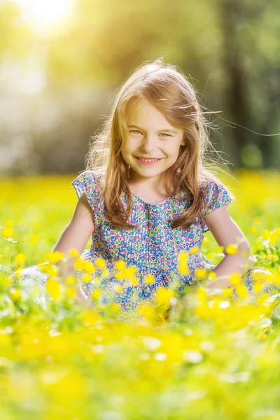 Glad liten tjej på blommande äng — Stockfoto