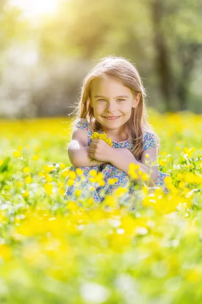 Glad liten tjej på blommande äng — Stockfoto