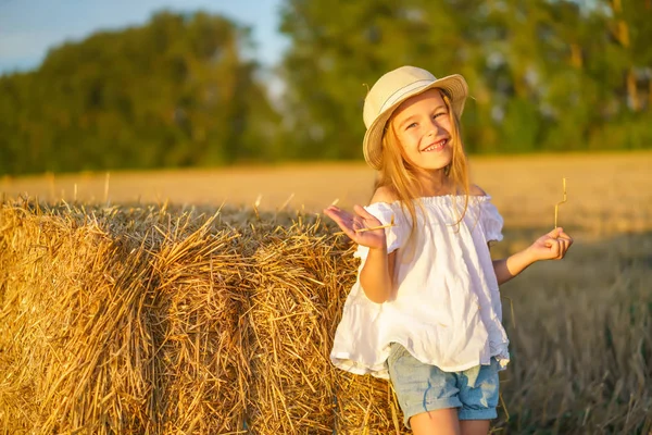 Niña en un campo con rollos de heno — Foto de Stock