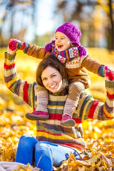 Mother and daughter playing in autumn park — Stock Photo, Image