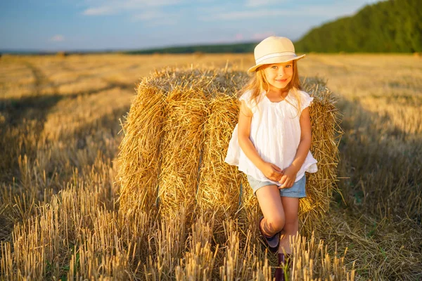 Little girl in a field with hay rolls — Stock Photo, Image