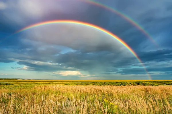 Rainbow over stormy sky in countryside at summer day — Stock Photo, Image