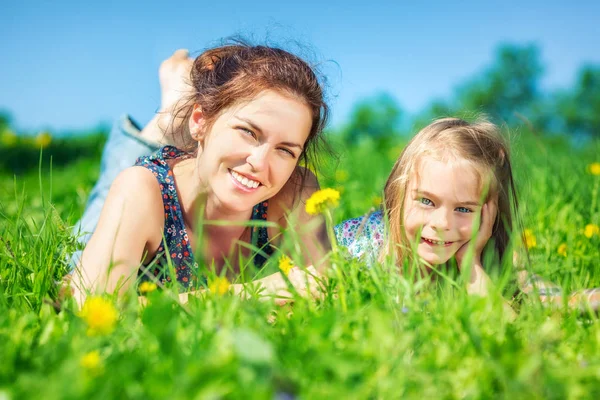 Mujer joven y su hija sobre hierba verde de verano — Foto de Stock