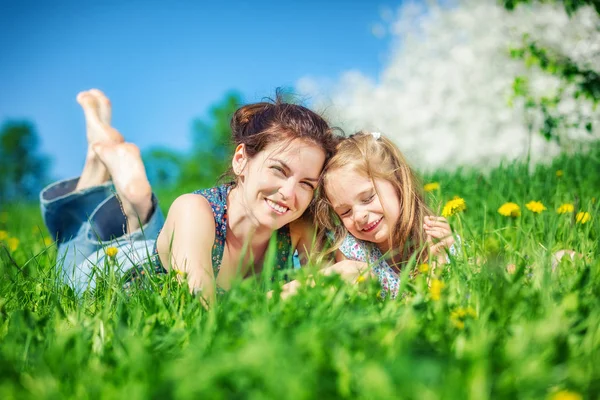 Mujer joven y su hija sobre hierba verde de verano —  Fotos de Stock