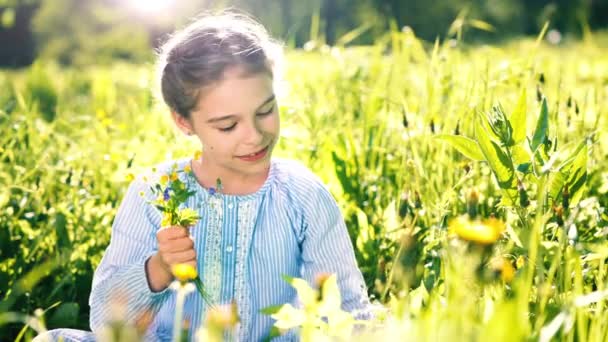 Mooi klein meisje spelen met bloemen in de zomer dag. — Stockvideo