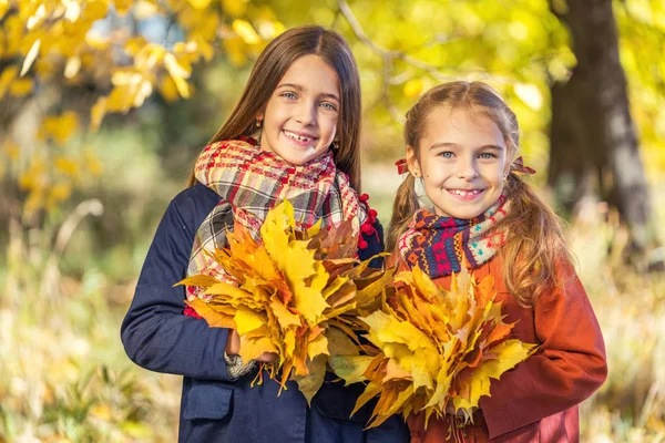 Dois sorrisos bonitos meninas de 8 anos posando juntas em um parque em um dia ensolarado de outono . — Fotografia de Stock