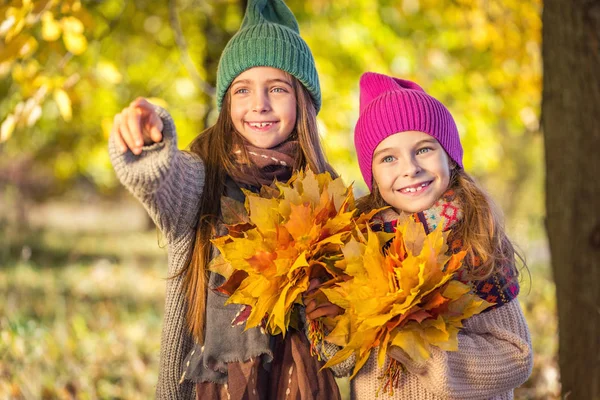 Zwei süße lächelnde 8-jährige Mädchen, die an einem sonnigen Herbsttag zusammen in einem Park spazieren gehen. — Stockfoto