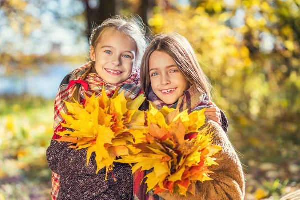 Two cute smiling 8 years old girls posing together in a park on a sunny autumn day. — Stock Photo, Image