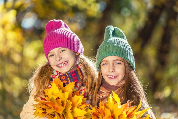 Две милые улыбающиеся 8-летние девочки позируют вместе в парке в солнечный осенний день . — стоковое фото