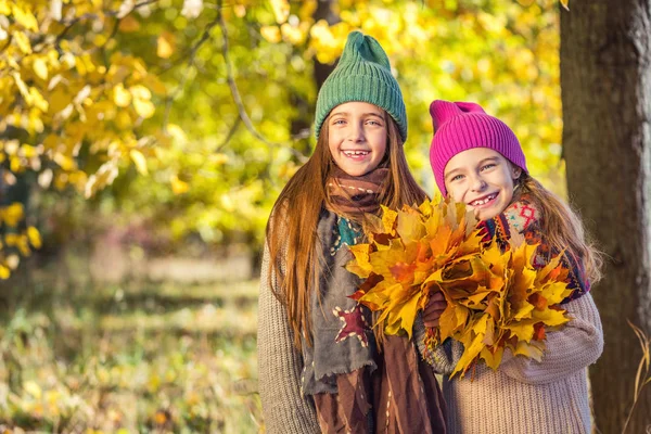 Dos chicas lindas sonrientes de 8 años posando juntas en un parque en un día soleado de otoño . — Foto de Stock