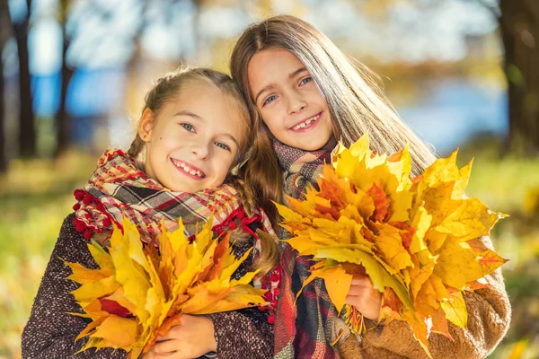 Zwei süße lächelnde 8-jährige Mädchen posieren zusammen in einem Park an einem sonnigen Herbsttag. — Stockfoto