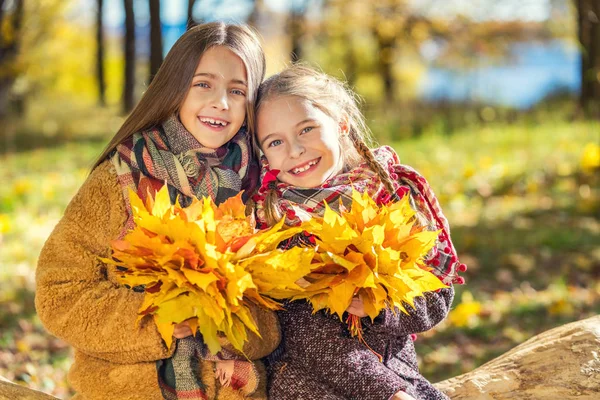 Dois sorrisos bonitos meninas de 8 anos posando juntas em um parque em um dia ensolarado de outono . — Fotografia de Stock