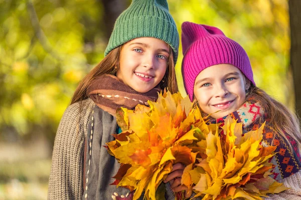 Two cute smiling 8 years old girls posing together in a park on a sunny autumn day. — Stock Photo, Image