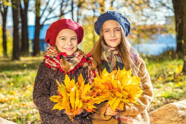 Two cute smiling 8 years old girls posing together in a park on a sunny autumn day. — Stock Photo, Image