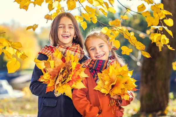 Dois sorrisos bonitos meninas de 8 anos posando juntas em um parque em um dia ensolarado de outono . — Fotografia de Stock