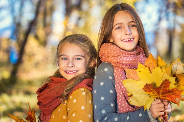 Dois sorrisos bonitos meninas de 8 anos posando juntas em um parque em um dia ensolarado de outono . — Fotografia de Stock