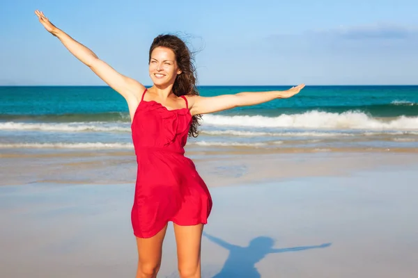 Fiatal nő piros ruhában élvezi a strandot — Stock Fotó