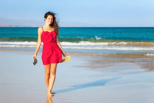 Jonge vrouw in rode jurk genieten van het strand — Stockfoto