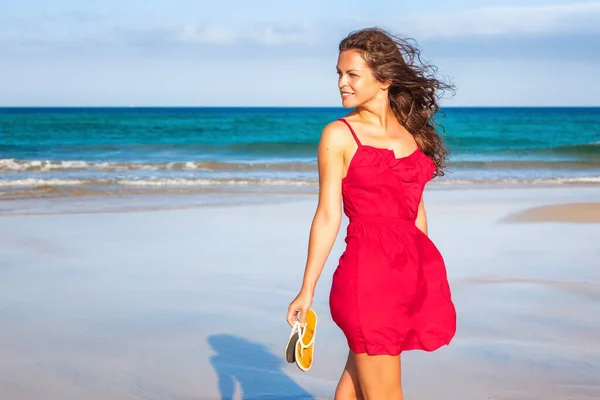 Jovem mulher de vestido vermelho desfrutando da praia — Fotografia de Stock