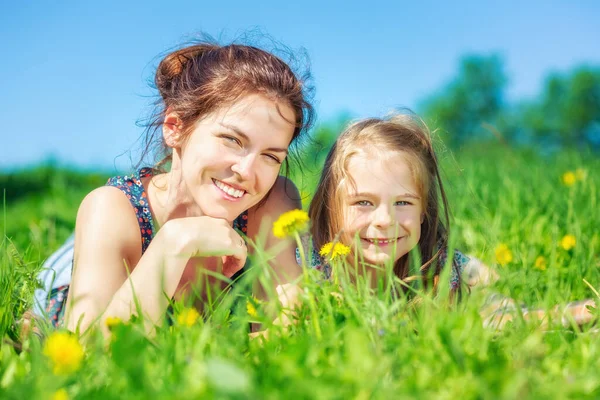 Mujer joven y su hija sobre hierba verde de verano — Foto de Stock