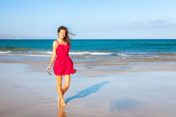Jovem mulher de vestido vermelho desfrutando da praia — Fotografia de Stock