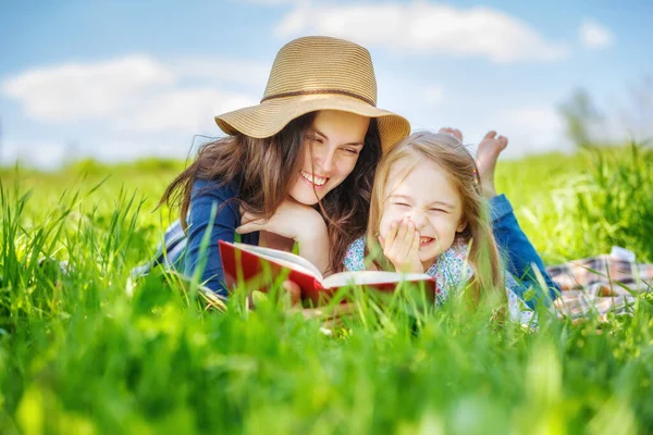 Moeder en dochter lezen boek over groene zomerweide — Stockfoto