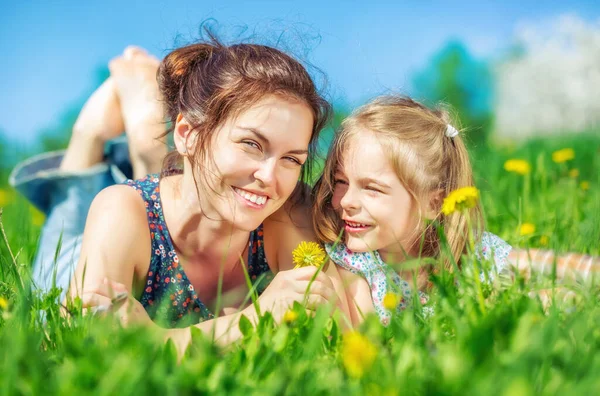 年轻女子和她的女儿在翠绿的夏草上 — 图库照片