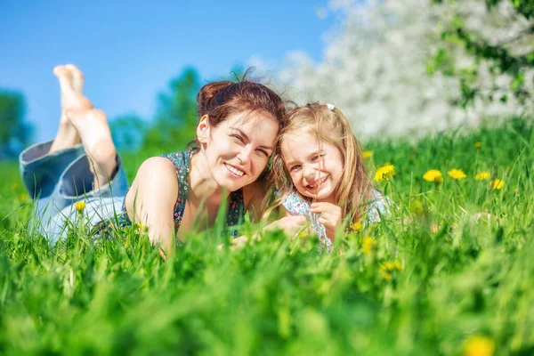 Mladá žena a její dcera na zelené letní trávě — Stock fotografie