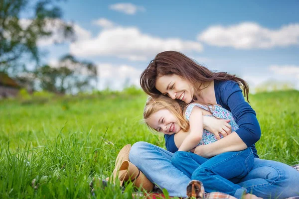 Moeder en dochter op voorjaarsweide met groen gras — Stockfoto