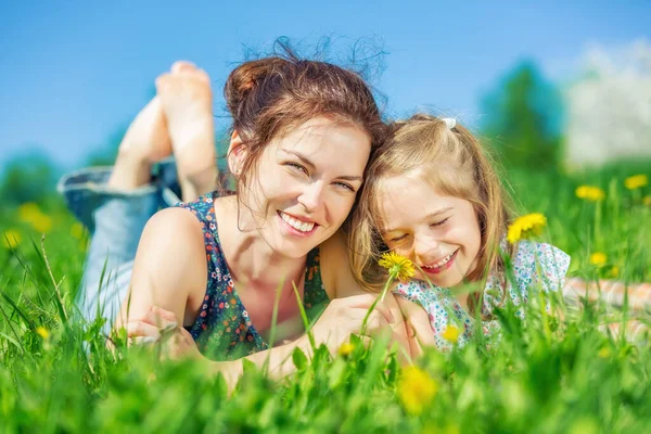 Mladá žena a její dcera na zelené letní trávě — Stock fotografie