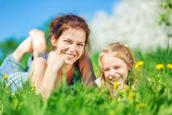 Mujer joven y su hija sobre hierba verde de verano —  Fotos de Stock
