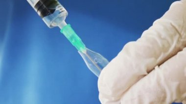 Doktorun elleri bir ampulden ilaçla şırınga dolduruyor 