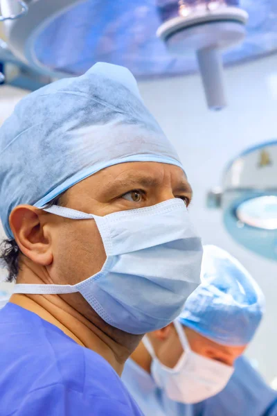 Cirurgião masculino de uniforme com máscara na sala de cirurgia — Fotografia de Stock