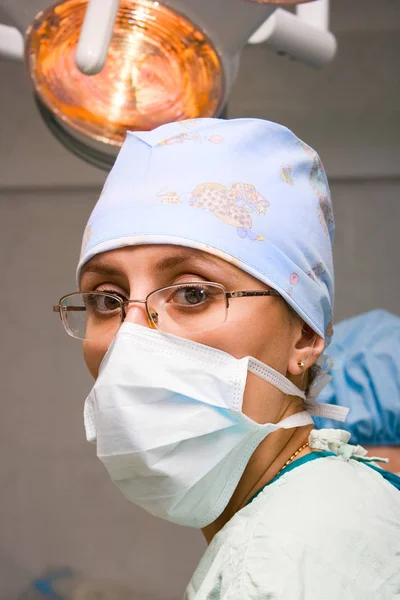 Młody żeński chirurg z maską w pomieszczeniu operacyjnym — Zdjęcie stockowe