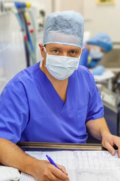 Mannelijke anesthesist in uniform schrijven van een medische grafiek — Stockfoto